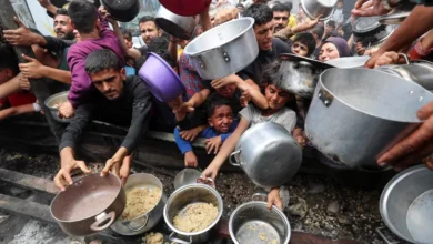 Palestinians wait to receive food cooked by a charity kitchen, in Jabalia, in the northern Gaza Strip, on May 14, 2025