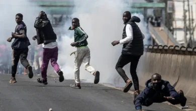 Protesters take cover amid clouds of tear gas fired by Kenyan police officers during clashes at Saba Saba Day demonstrations in Nairobi