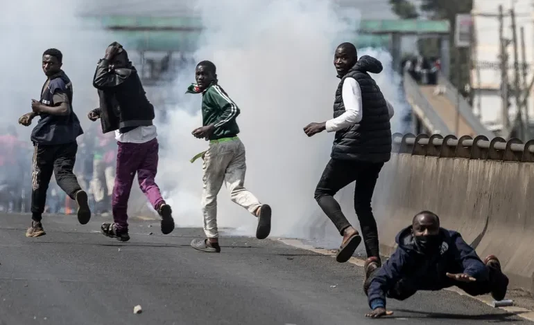 Protesters take cover amid clouds of tear gas fired by Kenyan police officers during clashes at Saba Saba Day demonstrations in Nairobi