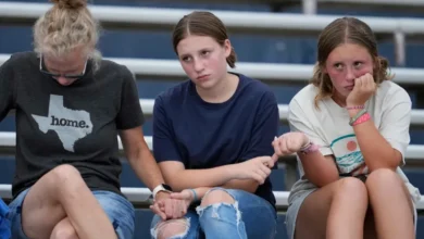 Attendees hold hands during a vigil for flooding victims at Tivy Antler Stadium on Wednesday, July 9, 2025, in Kerrville, Texas