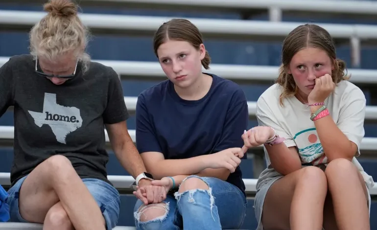 Attendees hold hands during a vigil for flooding victims at Tivy Antler Stadium on Wednesday, July 9, 2025, in Kerrville, Texas